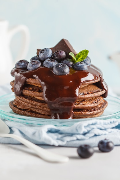 Crêpes au chocolat avec sirop de chocolat, lait et bleuets. Fond bleu, concept de petit déjeuner, espace copie