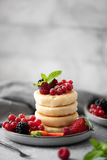 Crêpes au fromage cottage avec des baies fraîches et de la menthe sur une plaque grise