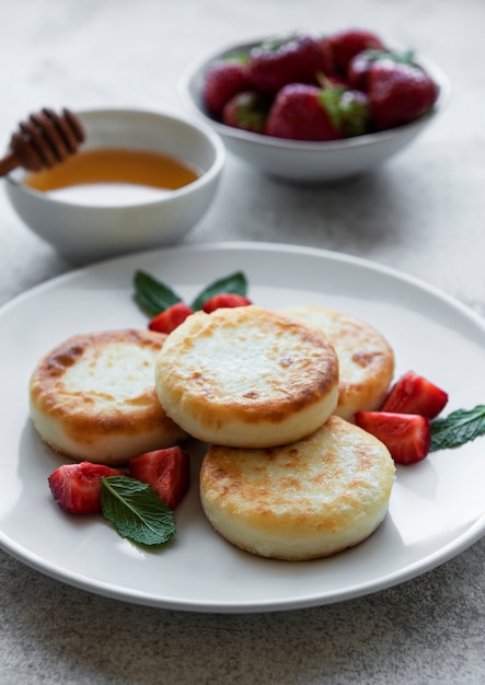 Crêpes au fromage cottage beignets de ricotta sur plaque en céramique avec fraise fraîche