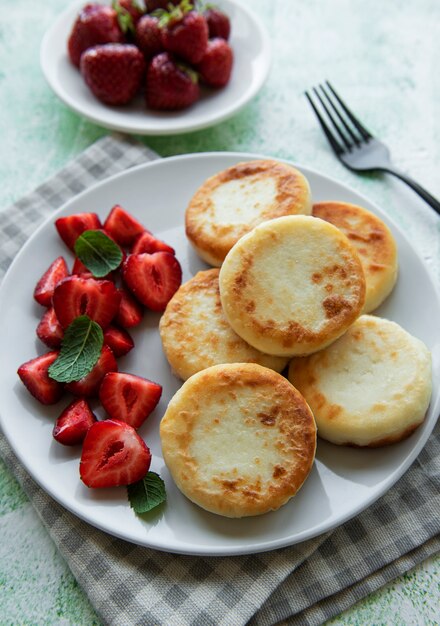 Crêpes au fromage cottage beignets de ricotta sur plaque en céramique avec fraise fraîche