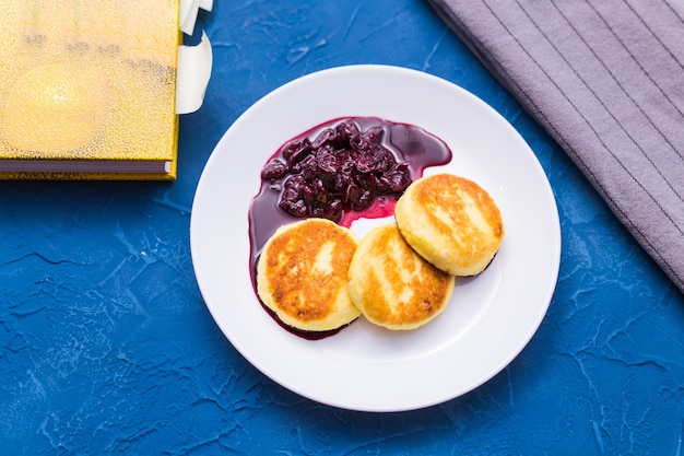 Crêpes au fromage cottage avec confiture de cerises, gros plan, vue de dessus.