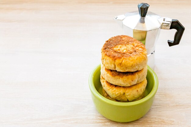 Crêpes au fromage cottage empilées dans un bol vert rond avec cafetière geyser