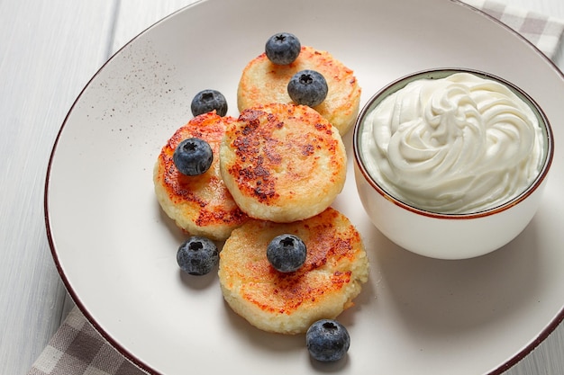 Crêpes au fromage cottage avec petit-déjeuner aux myrtilles sur une table en bois blanche sans personne vue de dessus