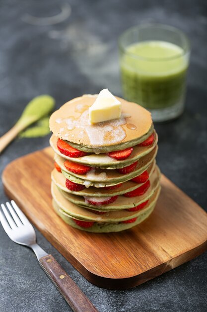 Crêpes au matcha maison avec des fraises et du beurre. Prêt pour le petit déjeuner.