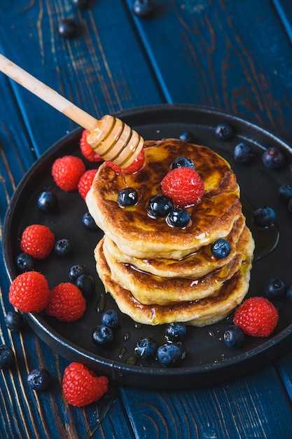 Crêpes au miel et baies sur une table en bois