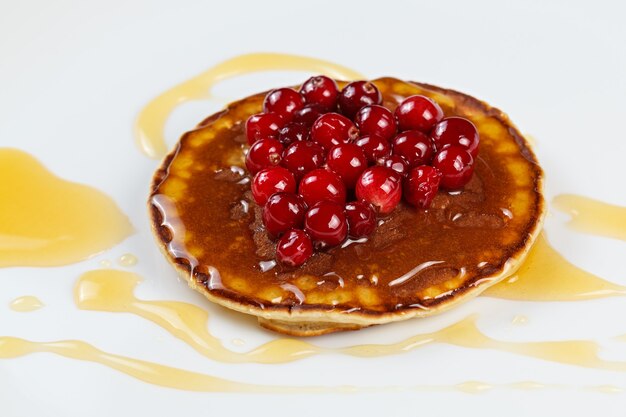 Crêpes au miel et canneberges sur une assiette.