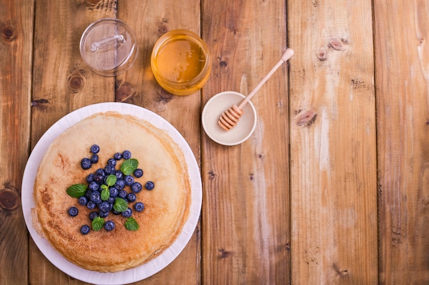 Crêpes aux bleuets et au miel sur une plaque, sur une toiture en bois