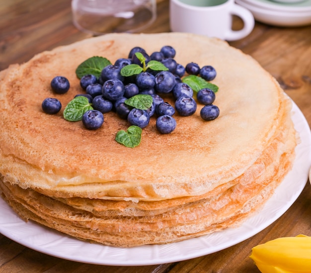 Crêpes aux bleuets et au miel sur une plaque, sur une toiture en bois