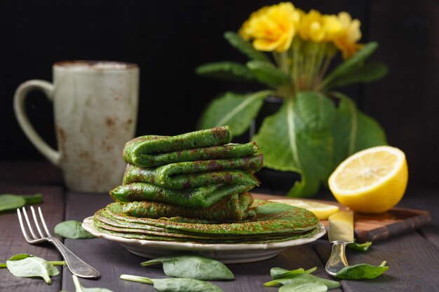 Crêpes aux épinards sur table en bois et primevère jaune.