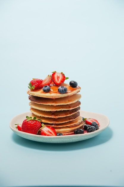 Crêpes aux fraises et bleuets sur fond bleu