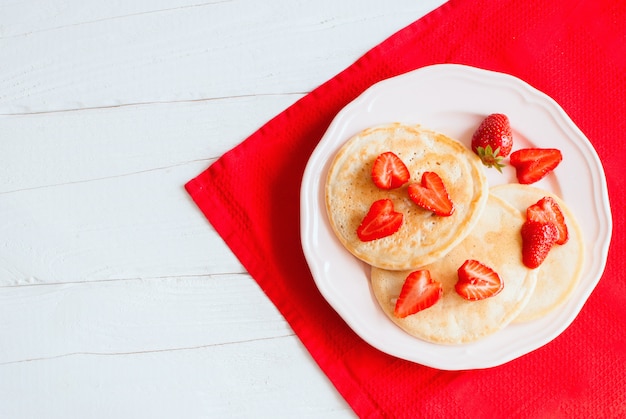 Crêpes aux fraises sur une table en bois blanc