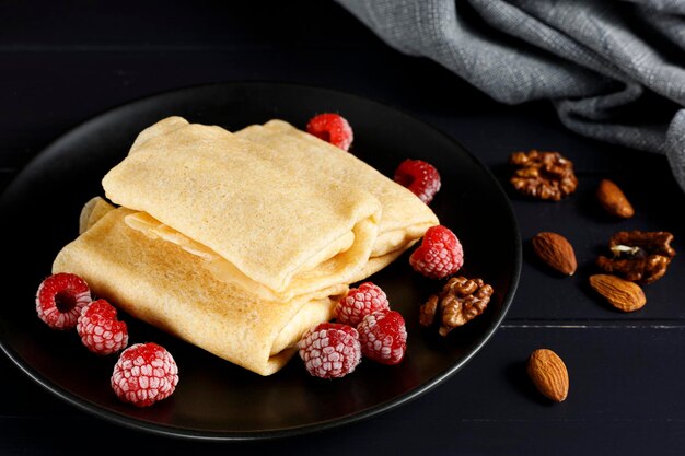 Crêpes aux framboises et noix sur une plaque noire dessert petit-déjeuner sain