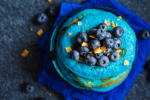 Crêpes aux myrtilles aux bleuets avec copeaux de noix de coco sur fond sombre.