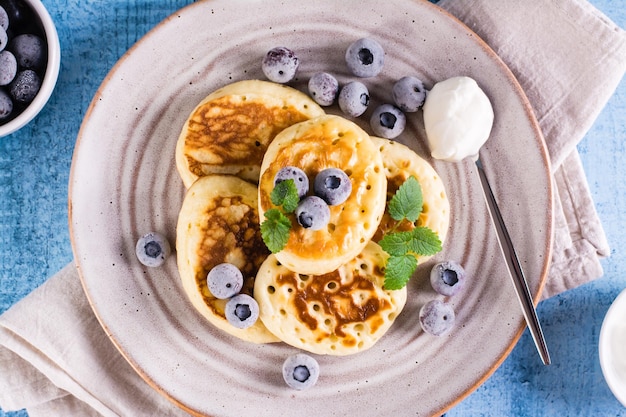 Crêpes aux myrtilles, crème sure et menthe sur une assiette Cuisson maison Vue de dessus Gros plan