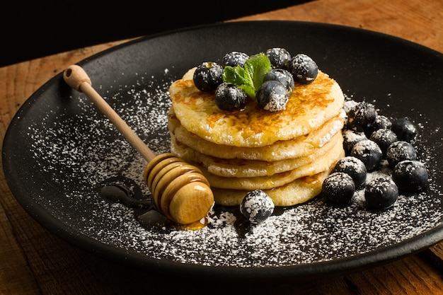 Crêpes aux myrtilles et sucre glace sur une plaque noire