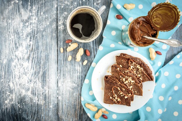 Crêpes d'avoine au chocolat avec caramel et noix sur table en bois gris.