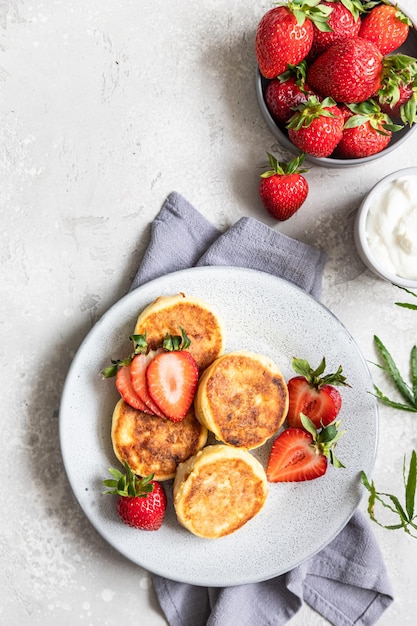 Crêpes ou beignets au fromage cottage avec fraises et yaourt nature Petit-déjeuner ou déjeuner sain