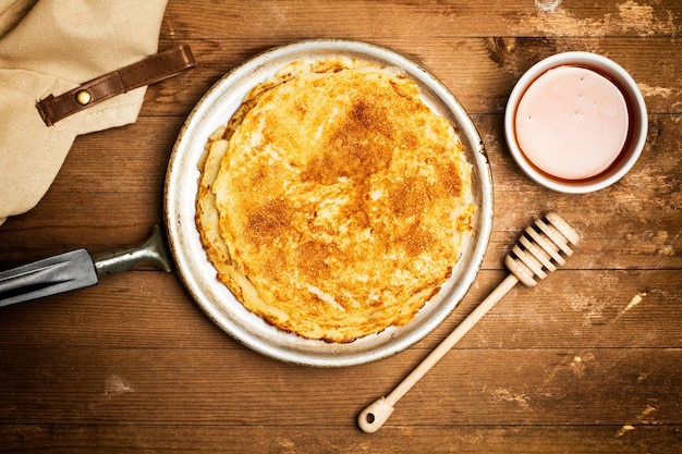 Crêpes et un bol de miel sur une table en bois