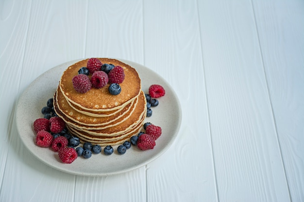 Crêpes classiques avec des baies fraîches sur une table en bois bleue. Crêpes aux fruits.