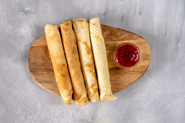 Crêpes à la confiture de framboises sur une planche de bois