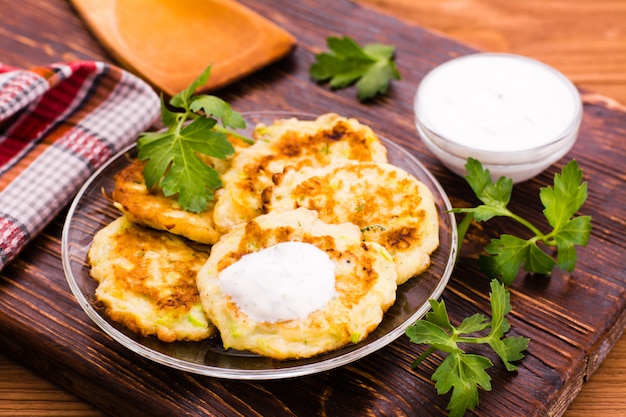 Crêpes de courgettes, sauce et persil sur une table en bois