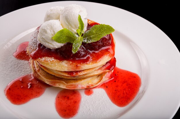 Crêpes à la crème glacée et confiture sur une plaque blanche