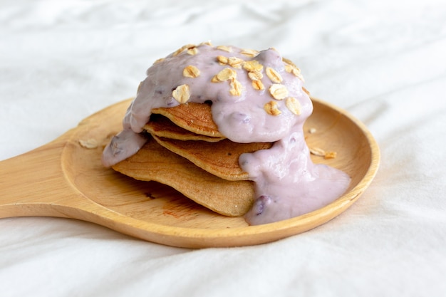 Crêpes diététiques maison avec yaourt aux fruits mélangés sur lit blanc le matin.