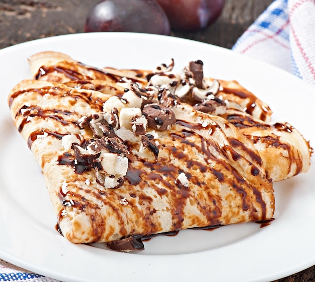 Des crêpes avec du sirop de chocolat et des prunes