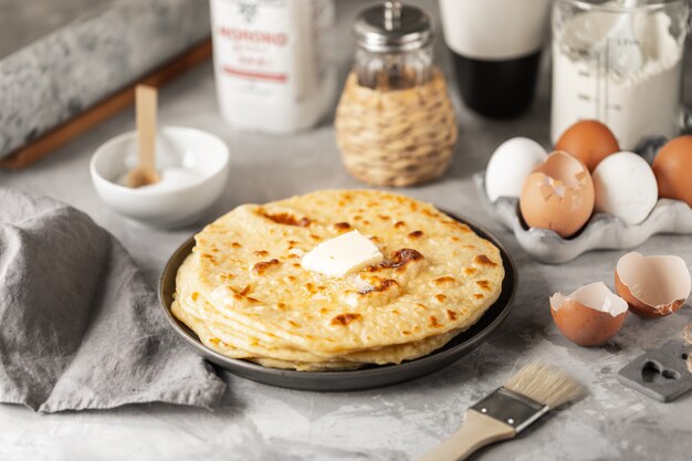 Crêpes empilées sur une assiette sur un tableau blanc avec une tasse de café et une bouteille de lait