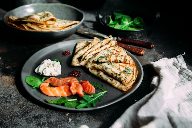 Crêpes fines aux herbes, saumon et fromage à la crème sur une assiette