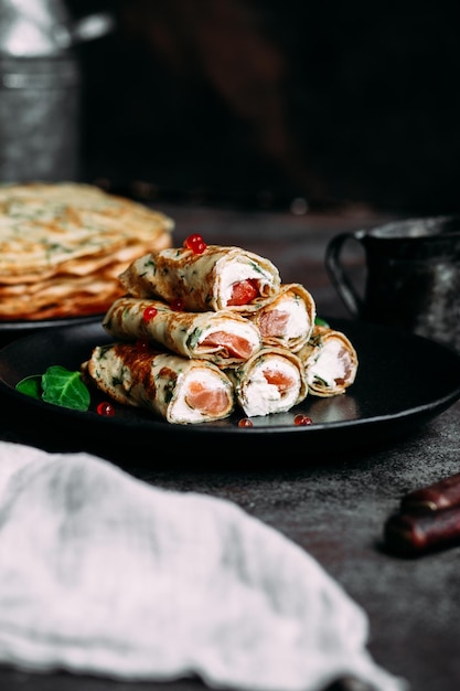 Crêpes fines aux herbes, saumon et fromage à la crème sur une assiette