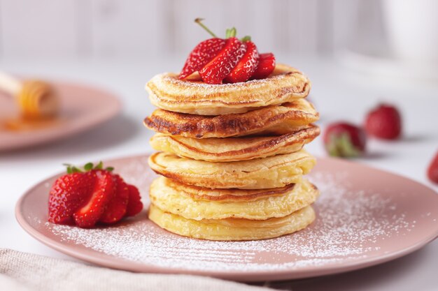 Crêpes fraîchement préparées avec des fraises sur un fond de bois naturel