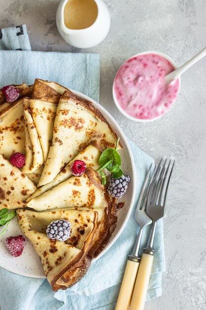 Crêpes françaises fraîchement faites maison (crêpes fines) avec des baies congelées et de la menthe pour le petit déjeuner