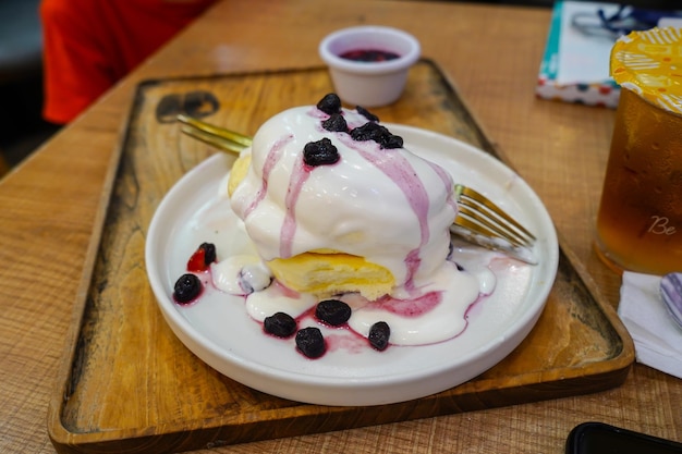 Crêpes japonaises moelleuses faites maison avec sauce aux baies et garniture de crème glacée sur une assiette blanche