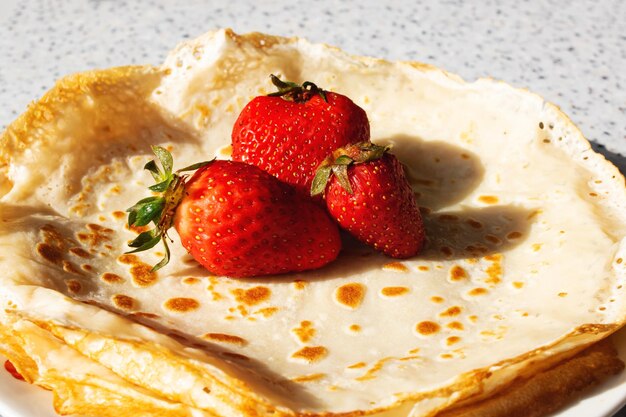 Crêpes jaunes et fraises sur une assiette