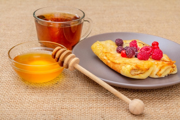 Crêpes maison au miel dans un bol et une tasse de thé