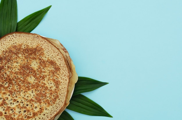 Crêpes maison sur bleu avec des feuilles vertes