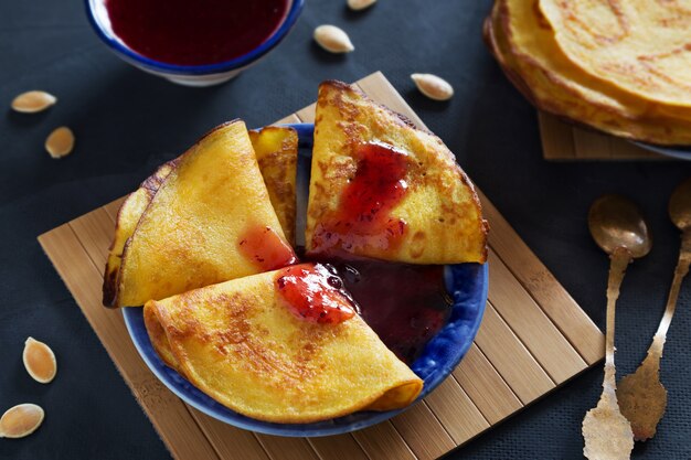 crêpes minces de citrouille avec confiture de baies sur la plaque bleue