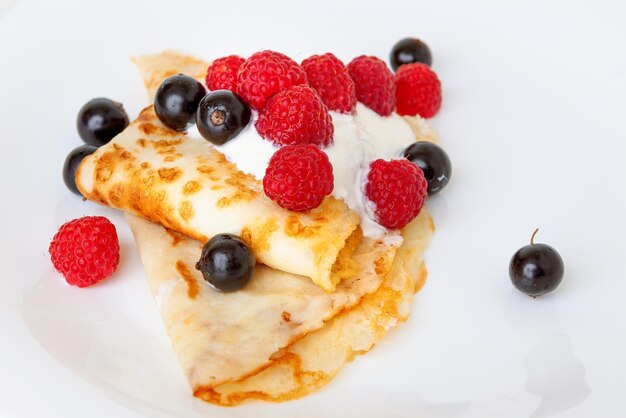 Photo des crêpes minces avec du raisin et de la sauce aux baies en gros plan