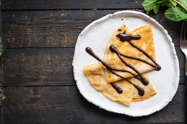 Crêpes minces verser le sirop de crêpes au chocolat gâteau plat plaque blanche