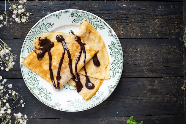 Photo crêpes minces verser le sirop de crêpes au chocolat gâteau plat plaque blanche