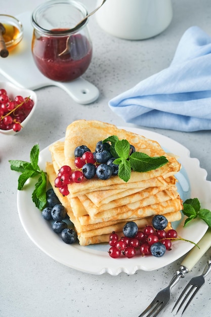 Crêpes Pile de crêpes ou crêpes fines aux baies myrtilles groseilles framboises et miel pour le petit-déjeuner Petit-déjeuner fait maison Espace de copie Mise au point sélective