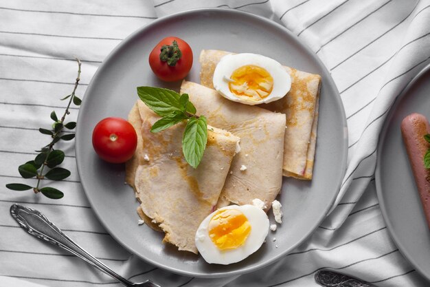 Photo crêpes plates avec œufs durs et tomates