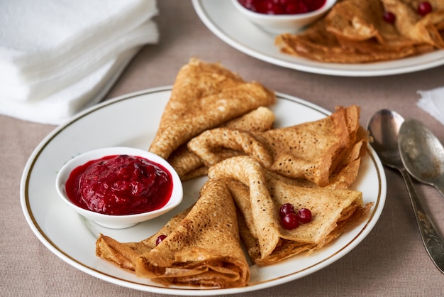 Crêpes à la sauce aux airelles sur une plaque blanche