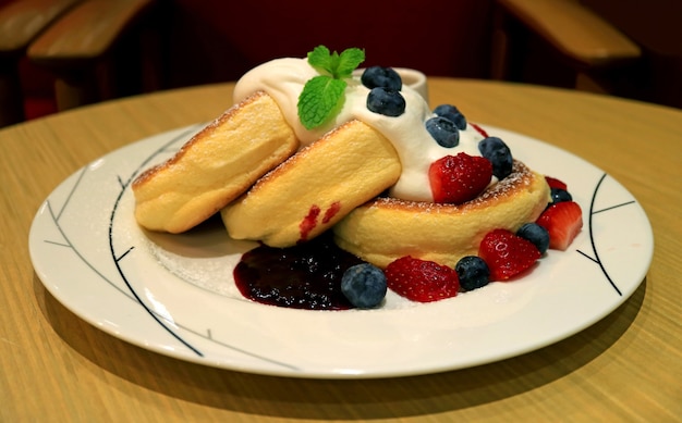 Crêpes soufflées moelleuses aux baies fraîches et crème de mascarpone servies sur une table ronde en bois