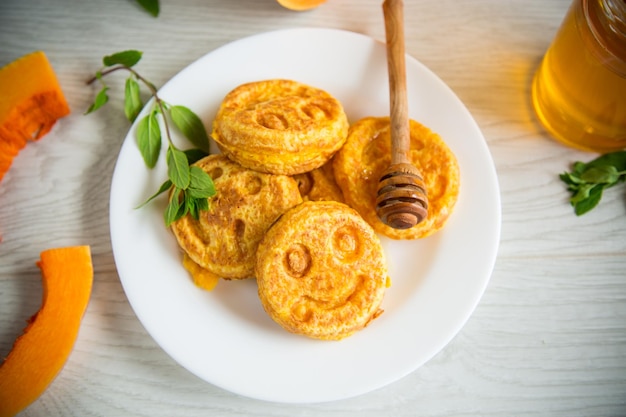 Crêpes sucrées à la citrouille luxuriante avec du miel dans une assiette sur une table en bois