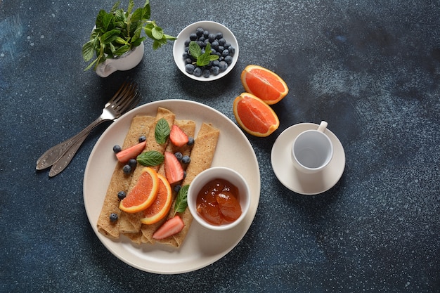 Crêpes sucrées enveloppées de menthe fraîche fraises myrtilles oranges et confiture