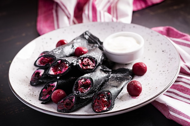 Crêpes sucrées à la ricotta et aux cerises. Crêpes noires. Petit déjeuner.