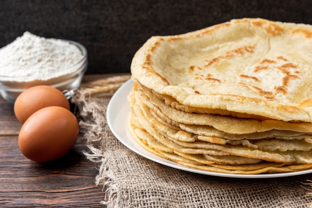 Crêpes sur table en bois avec des ingrédients à côté