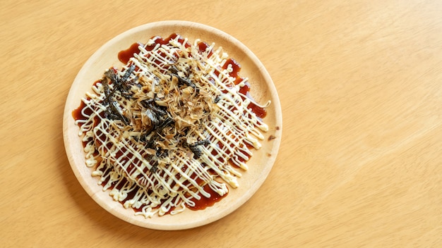 Crêpes traditionnelles japonaises (Okonomiyaki) sur une table en bois.